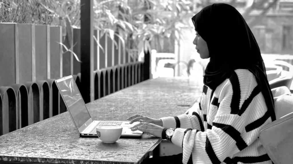 Shifa Henna, the best digital marketing analyst in Kuwait, working on a laptop with a cup of coffee beside her, representing focus and creativity in digital growth.